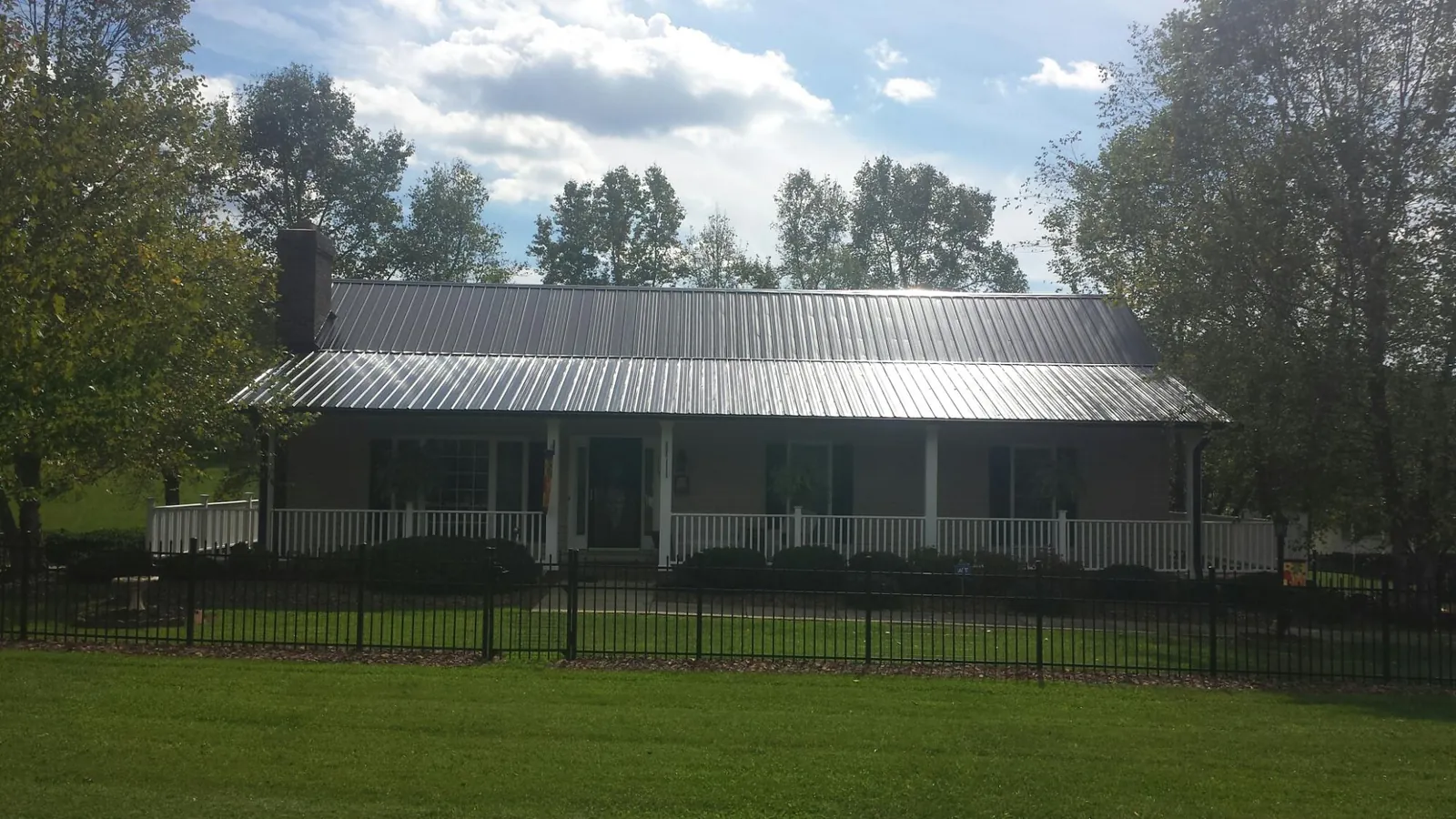 Gray metal roof on a brick ranch with a full width front porch — Gutter Guard Installation work by our crew in Ardmore